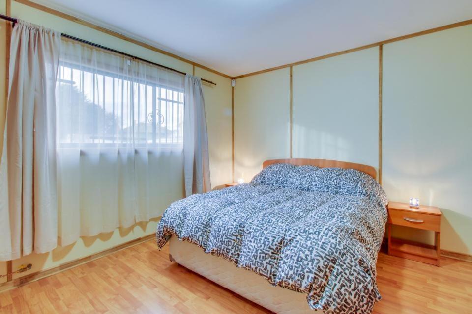 1 dormitorio con cama y ventana grande en Cabañas Las Heras, en Punta Arenas