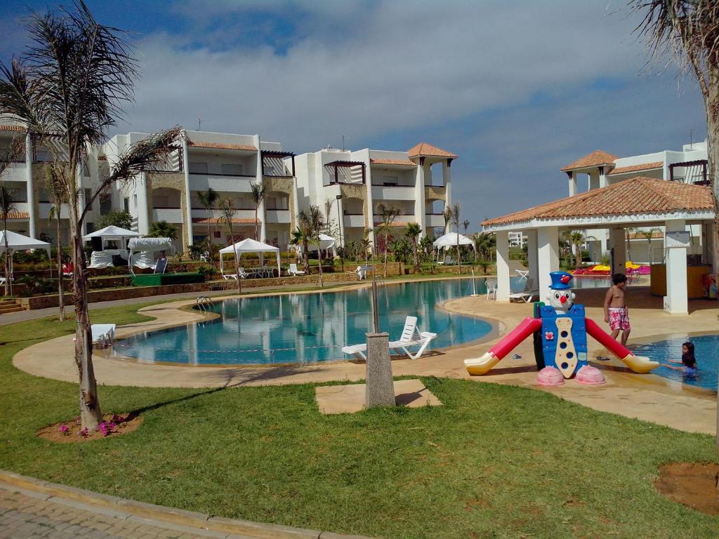 a resort with a pool with a slide and a playground at Marina golf Assila in Asilah