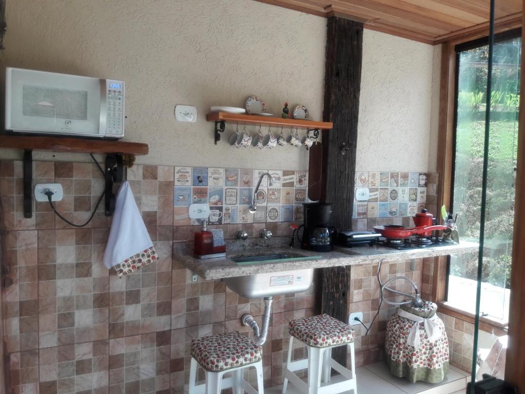 a kitchen with a sink and a counter with stools at Pousada Cores e Flores da Serra in Santo Antônio do Pinhal