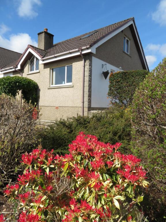 a house with red flowers in front of it at Orasaidh Apartment in Stornoway