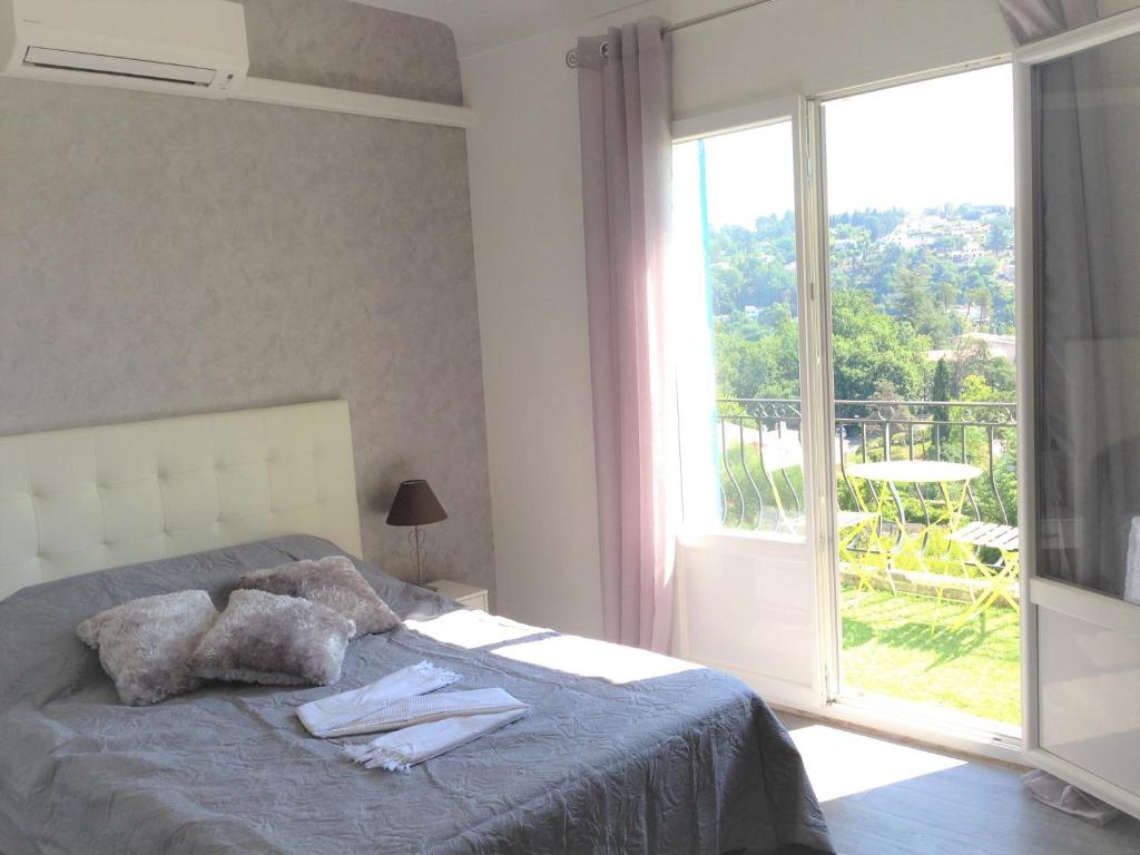 a bedroom with a bed and a large window at La Vençoise in Vence