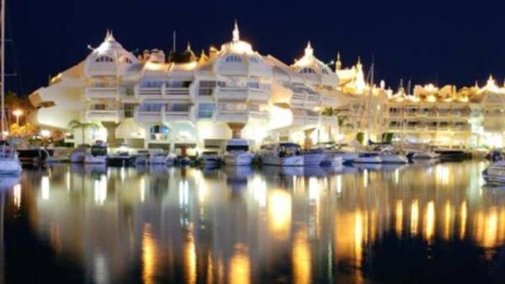 a large building with boats in a marina at night at Malva Loca Apartment in Benalmádena