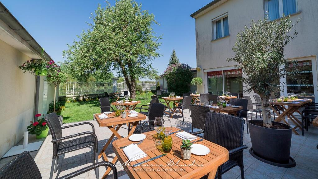 een patio met tafels, stoelen en bomen bij Beau Rivage in Nogent-sur-Seine