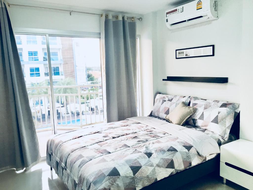 a bedroom with a bed and a large window at Grandbeach Condo Unite A307 in Rayong