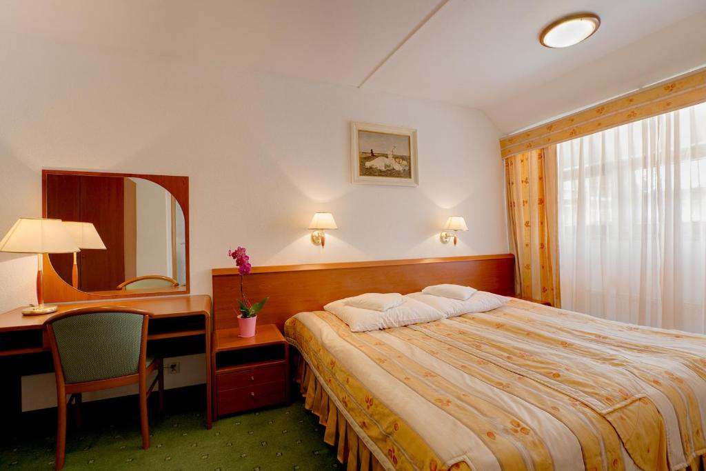 a hotel room with a bed and a desk and a mirror at Hotel Zajazd Piastowski in Kazimierz Dolny