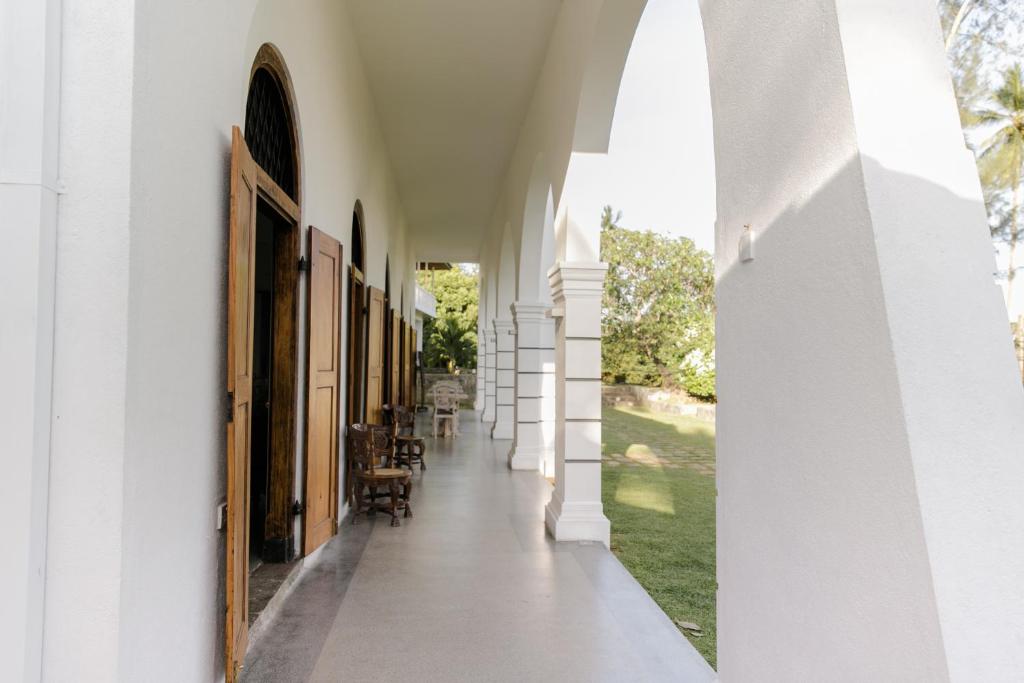 an empty hallway of a white building with an open doorway at Nuga Eden Tangalle in Tangalle
