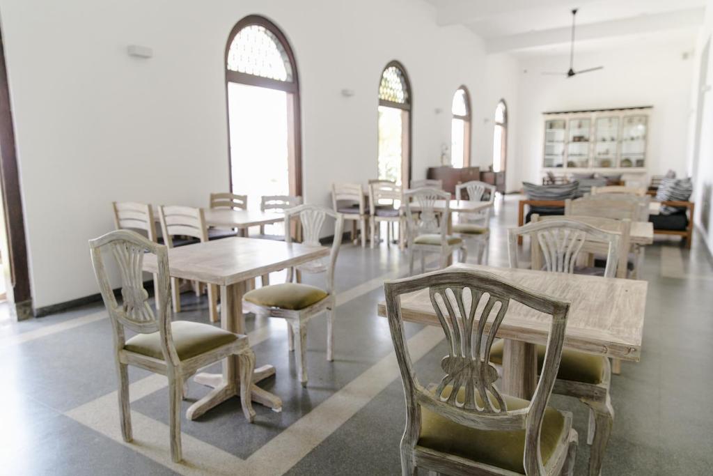 a dining room with tables and chairs and windows at Nuga Eden Tangalle in Tangalle