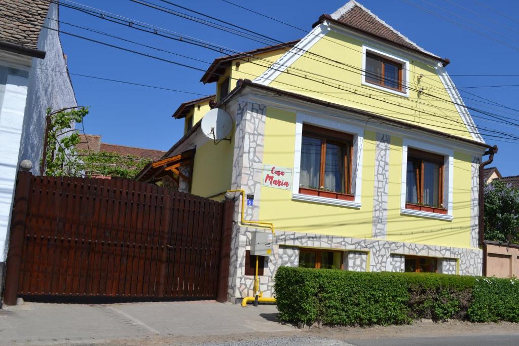 a yellow house with a fence in front of it at Casa Maria in Şura Mică