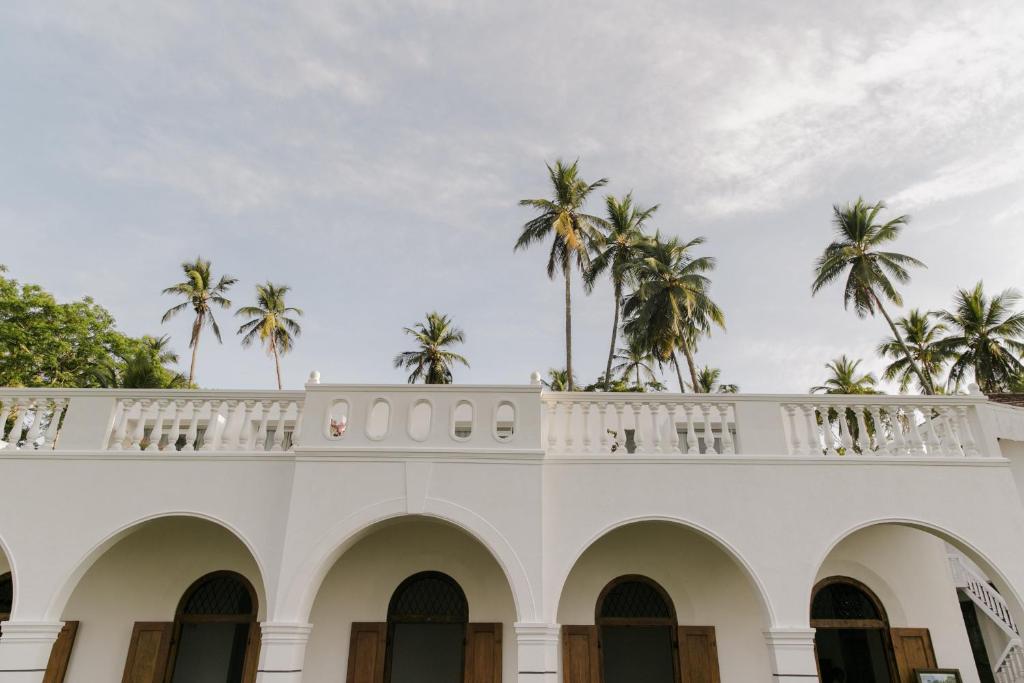 a white building with palm trees on the top at Nuga Eden Tangalle in Tangalle