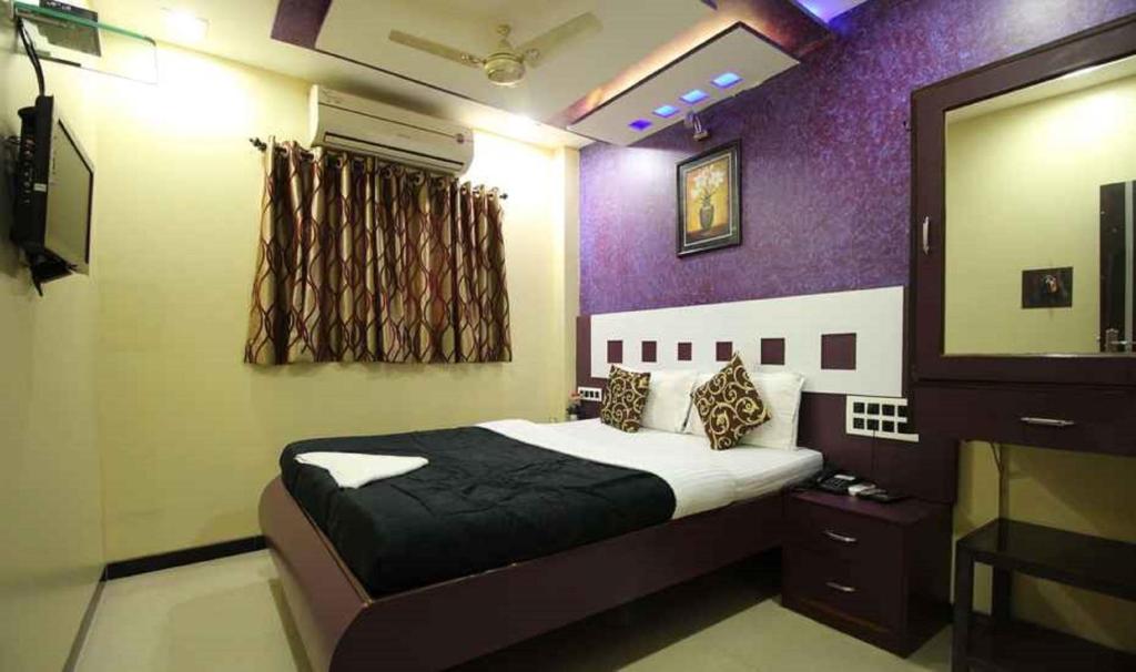 een slaapkamer met een bed met een paarse muur bij Hotel Planet Plaza in Mumbai