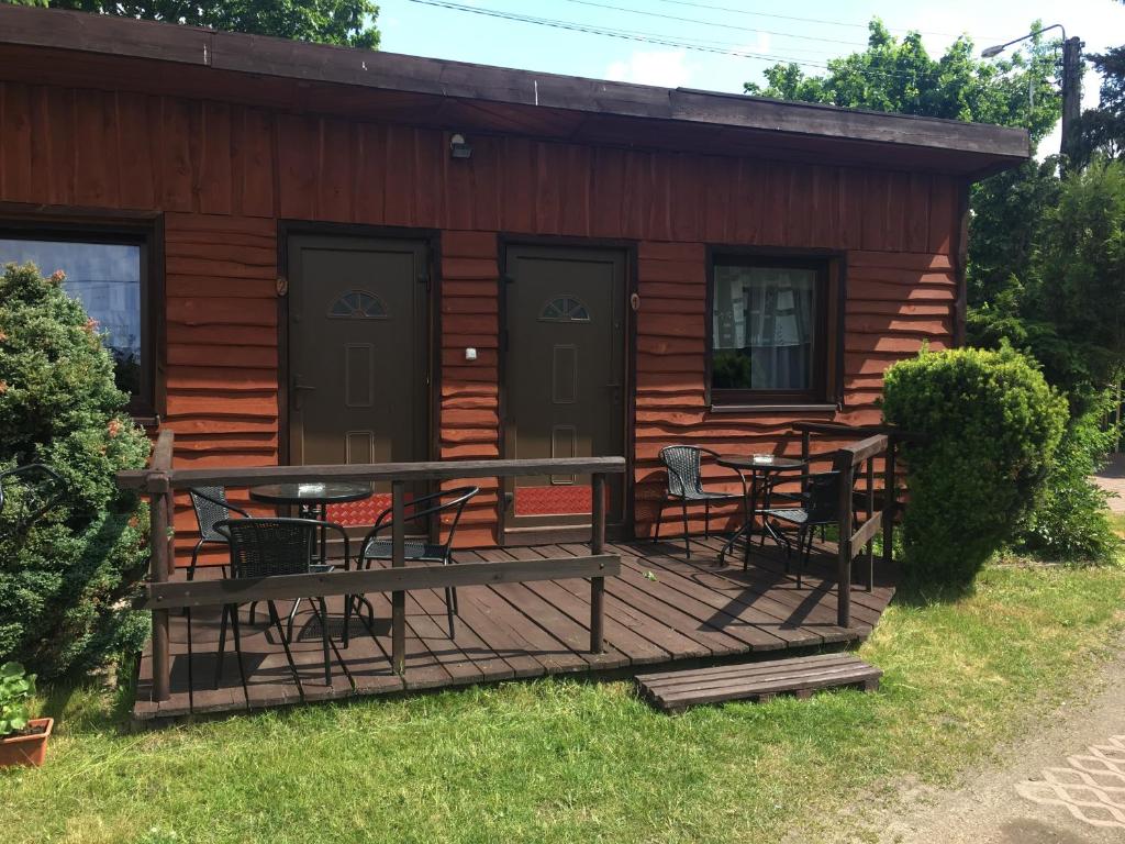 a cabin with a deck with chairs and a table at Orle Gniazdo domki in Stegna