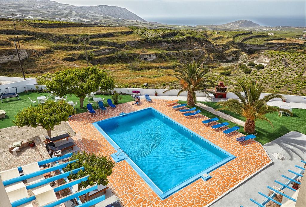 an aerial view of a swimming pool with chairs and trees at Zorbas Hotel Santorini in Pirgos