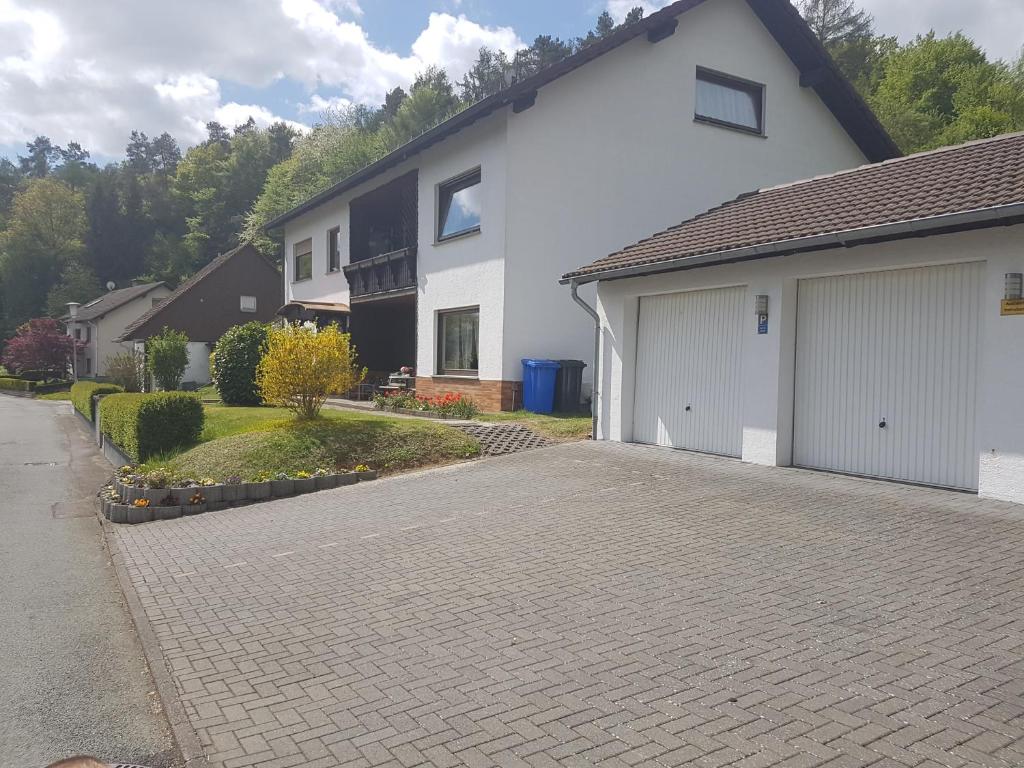 une maison blanche avec un garage et une allée dans l'établissement Ferienwohnung La Le Lu, à Hemfurth-Edersee