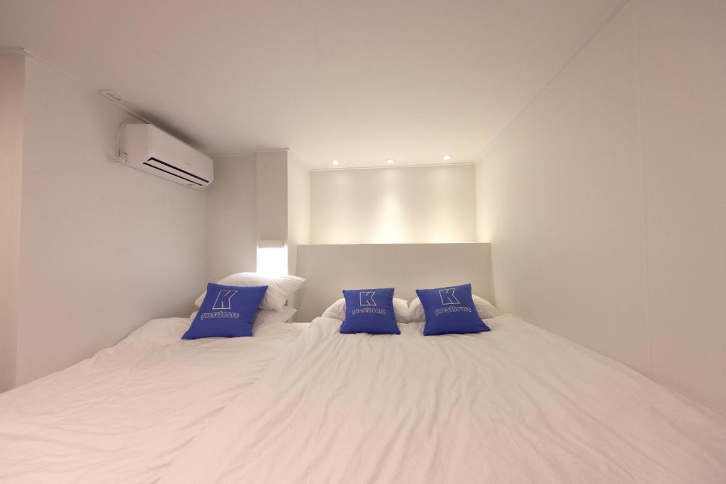 a bedroom with a large white bed with blue pillows at K-Guesthouse Myeongdong 1 in Seoul