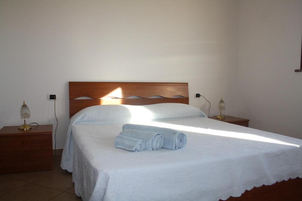 een slaapkamer met een groot wit bed en 2 handdoeken bij Il Giardino in Riotorto