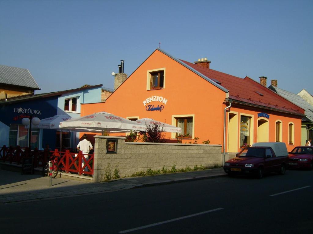 un hombre parado fuera de un edificio naranja con un paraguas en Apartmán 1, třílůžkový s přistýlkou s kuchyní a koupelnou en Frenštát pod Radhoštěm