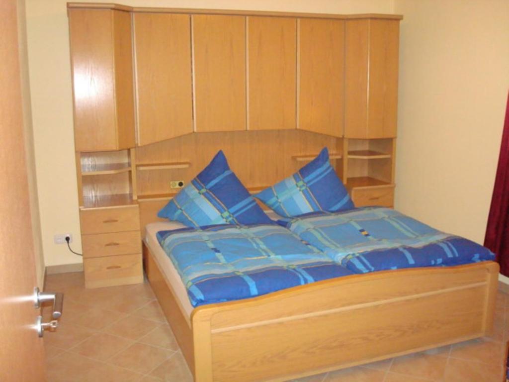 1 dormitorio con 1 cama con cabecero de madera y almohadas azules en Ferienwohnung Michael Meißner ruhig, gemütlich und kinderfreundlich, en Crottendorf