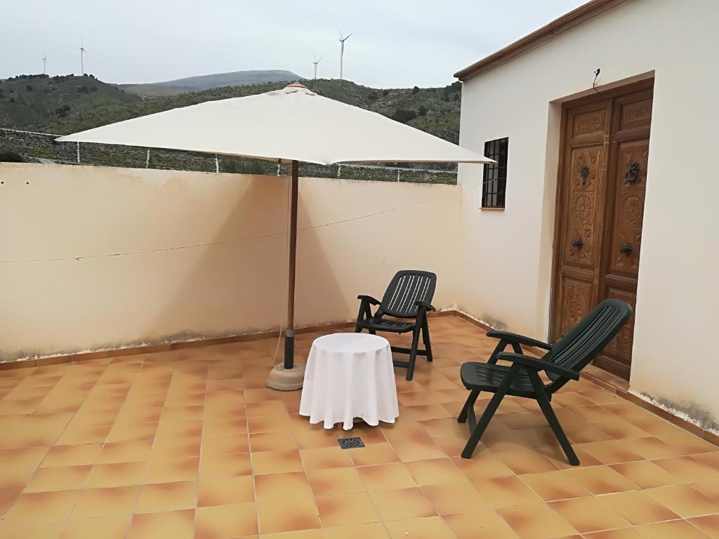 einen Tisch mit Stühlen und einen Regenschirm in einem Zimmer in der Unterkunft PERGAR DESCANSO-15 minutos Playa-Motril Ferry in Acebuches