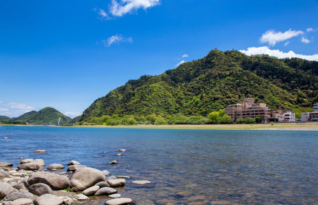 une montagne avec une maison sur la rive d'un lac dans l'établissement Hotel Park, à Gifu