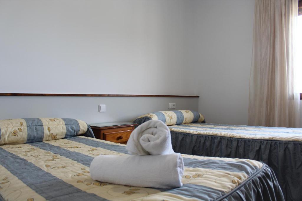 Habitación de hotel con 2 camas y toallas. en Hostal Mirobriga, en Ciudad Rodrigo