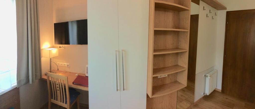 a room with a closet with a desk and a television at Hotel Garni Wurzer in Velden am Wörthersee