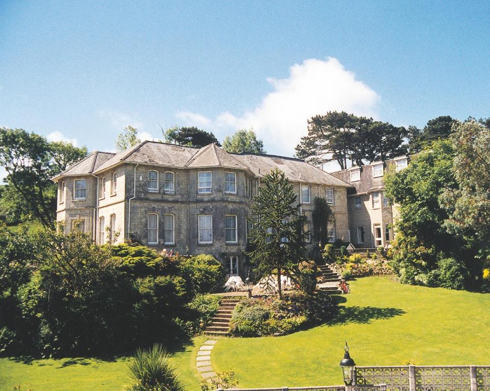 a large stone house with a lawn in front of it at Bourne Hall Country Hotel in Shanklin
