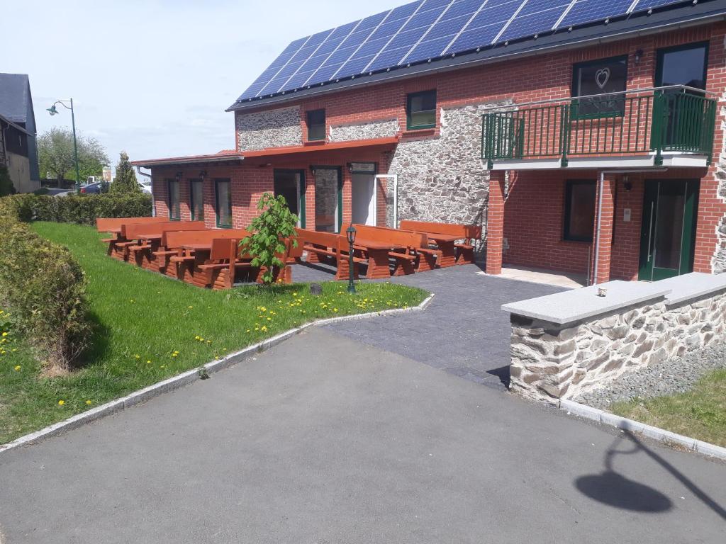 a group of benches in front of a building with solar panels at Hirt's Brau-& Gasthof in Remptendorf