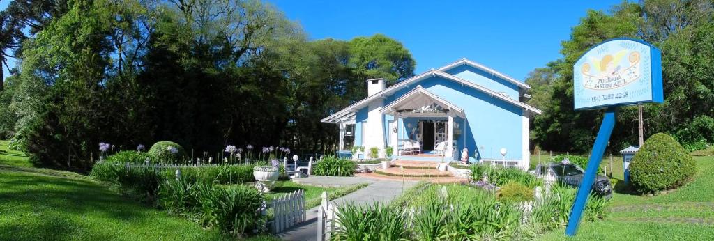 una pequeña casa azul con un cartel en un jardín en Pousada Jardim Azul, en Canela