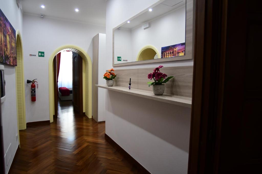 um corredor com paredes brancas e flores nas prateleiras em Royal Termini em Roma