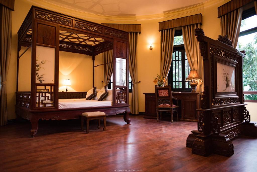 - une chambre avec un grand lit à baldaquin dans l'établissement Spring Garden Villa, à Hue