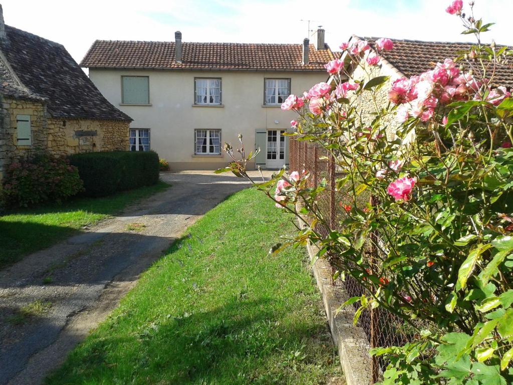 una casa con una valla y un arbusto con flores rosas en Gîte de Bazeille, en Saint-Avit-Sénieur
