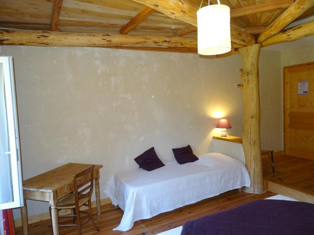 - une chambre avec un lit blanc et un plafond en bois dans l'établissement Le hameau de Robert, à Boucieu-Le-Roi