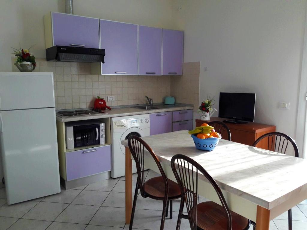 una cucina con armadietti viola e tavolo con sedie di Residence Onda Blu a Cervia