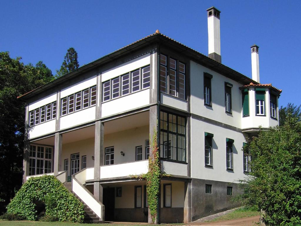 a white building with two chimneys on top of it at Quinta das Colmeias in Santo da Serra