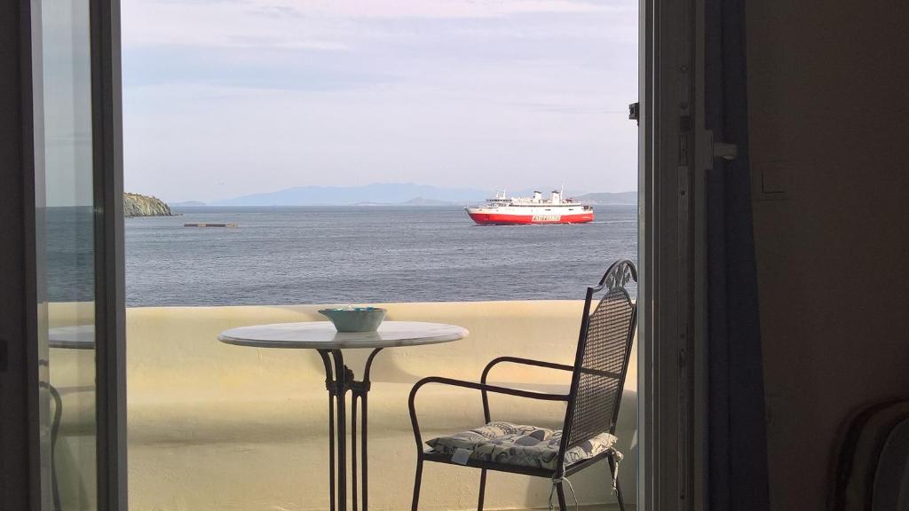 a balcony with a table and a boat in the water at Parathyro sto Aigaio 2 - Small Suites in Tinos Town