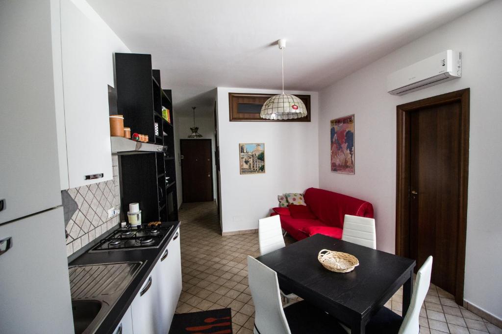 a kitchen and dining room with a table and a red couch at La Marina House - Al Duomo in Catania