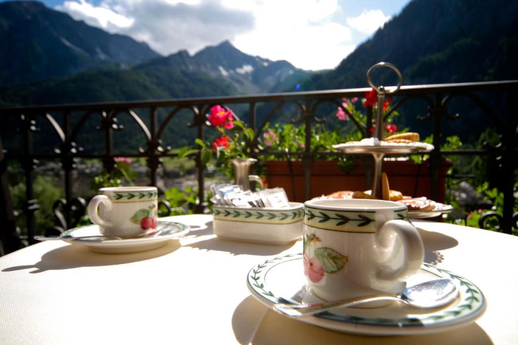 a table with cups and saucers on top of a balcony at Villa Novecento Romantic Hotel - Estella Hotel Collection & Experience in Courmayeur