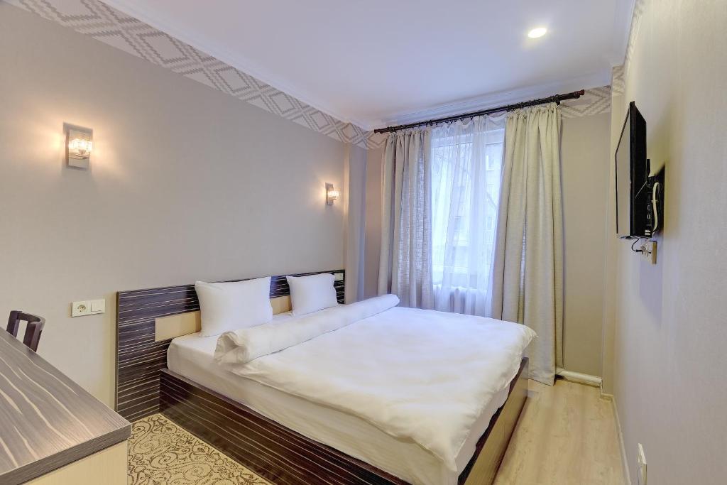 a bedroom with a large white bed and a window at Resident Hotel Almaty in Almaty