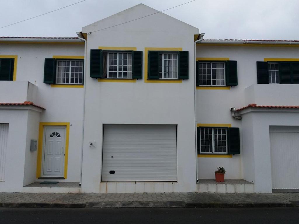 ein weißes Haus mit zwei Garagentüren und Fenstern in der Unterkunft Casa dos Rui´s in Velas