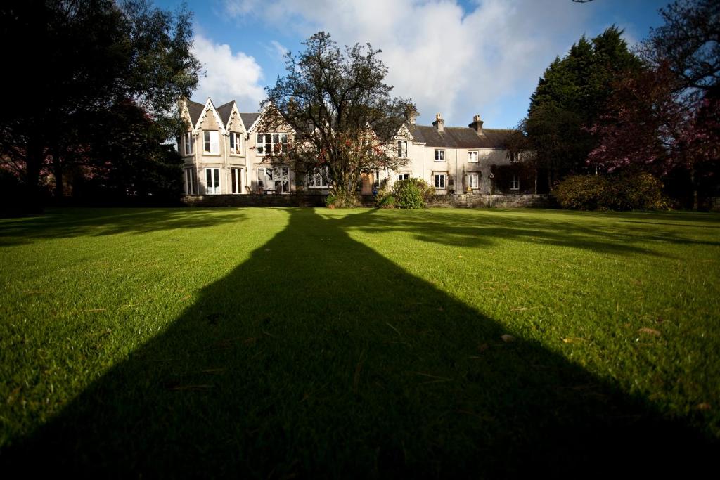 a long shadow of a house on a field of grass at Parc-Le-Breos House in Penclawdd