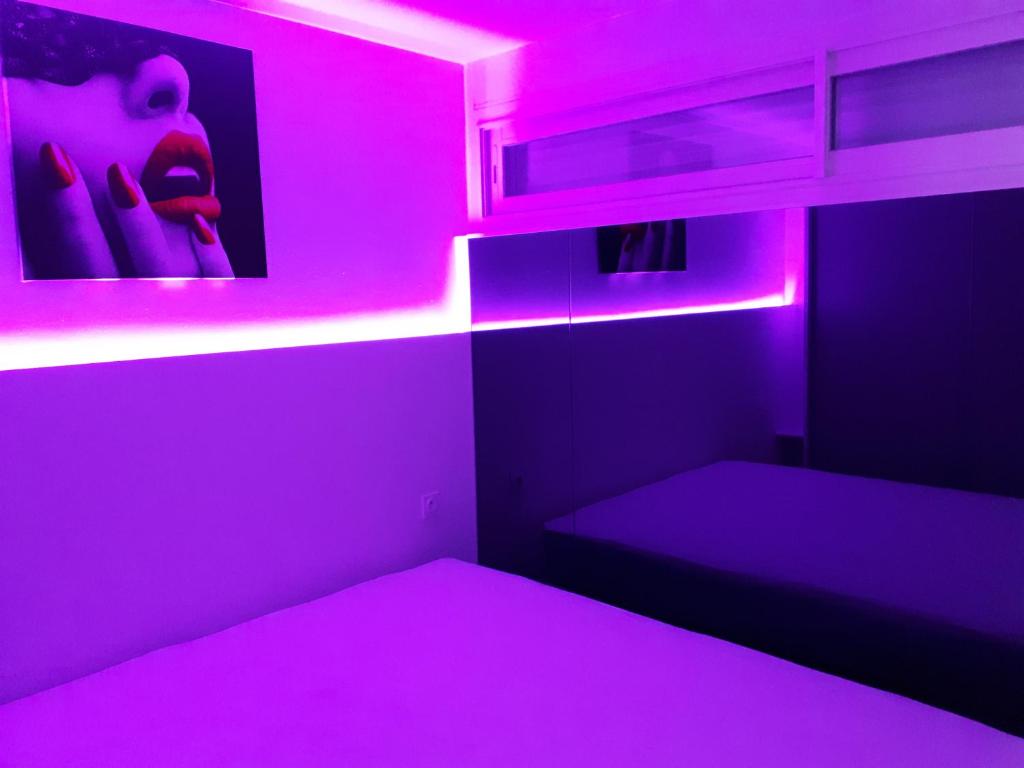 カップ・ダグドにあるMagnifique Appartement CAP NATURISTEのピンクの照明と二段ベッドが備わる客室です。