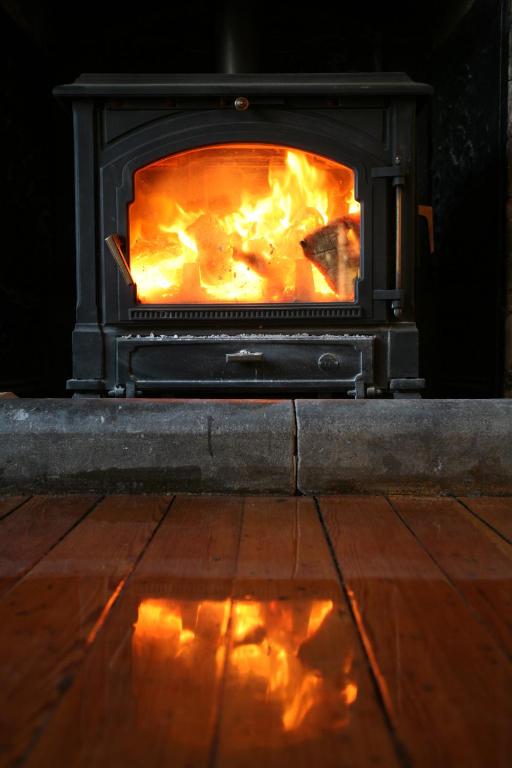 a stove with a fire in it in a room at Parc-Le-Breos House in Penclawdd