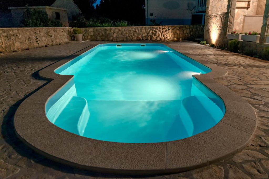 a swimming pool with blue water in a driveway at Apartman Herhenreder in Stari Grad