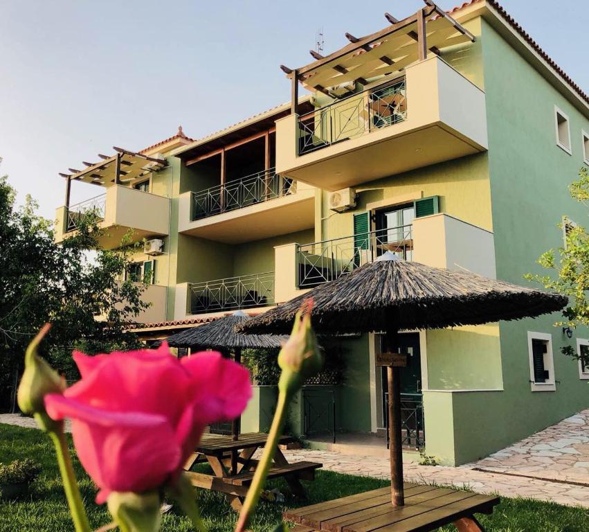 Galini Apartments في ترابيزاكي: وردة وردية ومظلة أمام المبنى