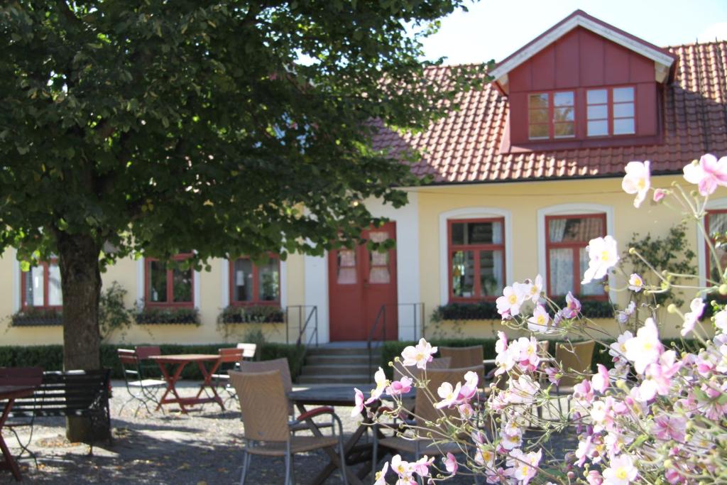 a house with tables and chairs and pink flowers at Blåsingsborgs Gårdshotell in Kivik