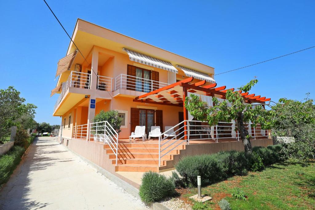 une maison avec une terrasse couverte et des escaliers en face de celle-ci dans l'établissement Apartments Villa Mareta, à Sukošan