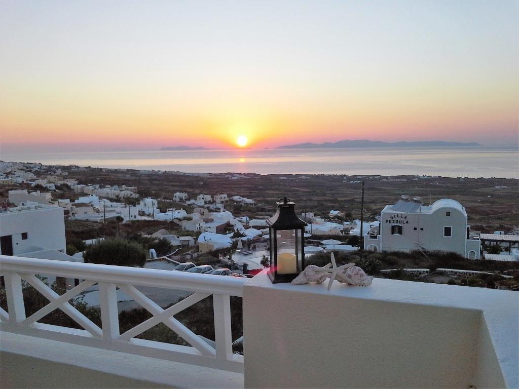 a lantern on a balcony with the sunset in the background at Kiklamino Sunset Studios in Oia