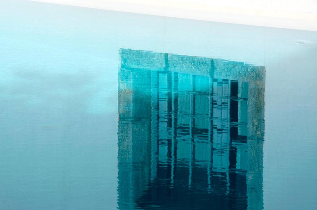 a reflection of a building in the water at Orloff Resort in Spetses