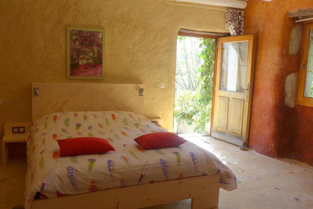 a bedroom with a bed with two red pillows at La Colline Bleue in Banne