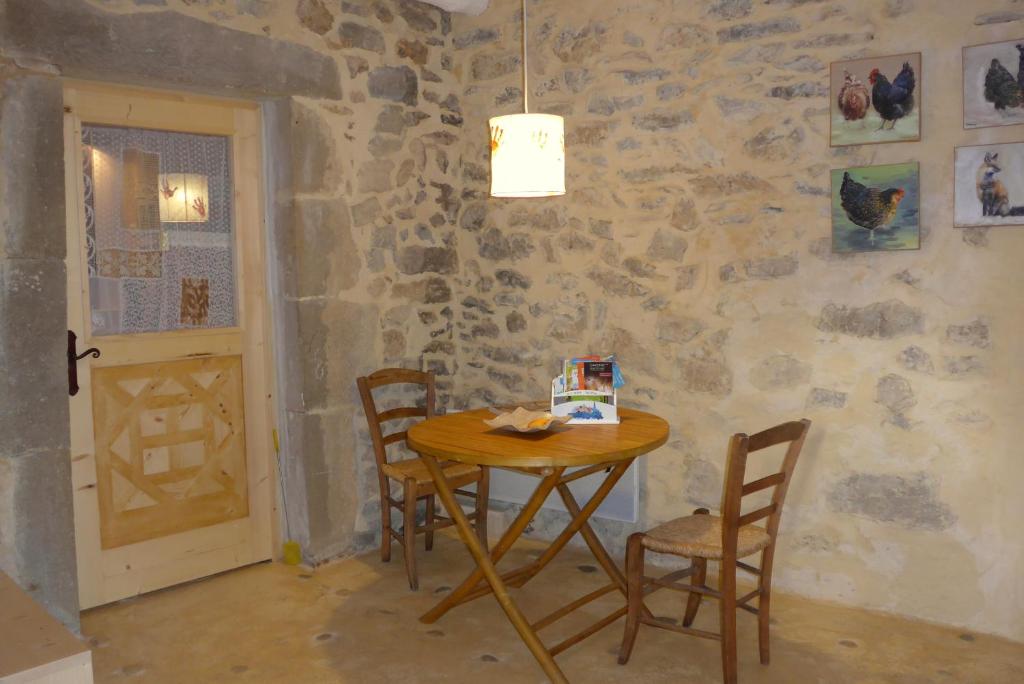 a table and chairs in a room with a stone wall at La Colline Bleue in Banne
